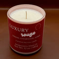 A textural image of a luxury rouge candle with a glowing flame, surrounded by a warm, inviting ambiance. Text overlay reads: "Introducing our new luxury rouge candle - the ultimate indulgence for candle lovers. Slow-burning formula fills your home with opulent fragrance. Perfect for unwinding or creating romantic ambiance. Order yours today!